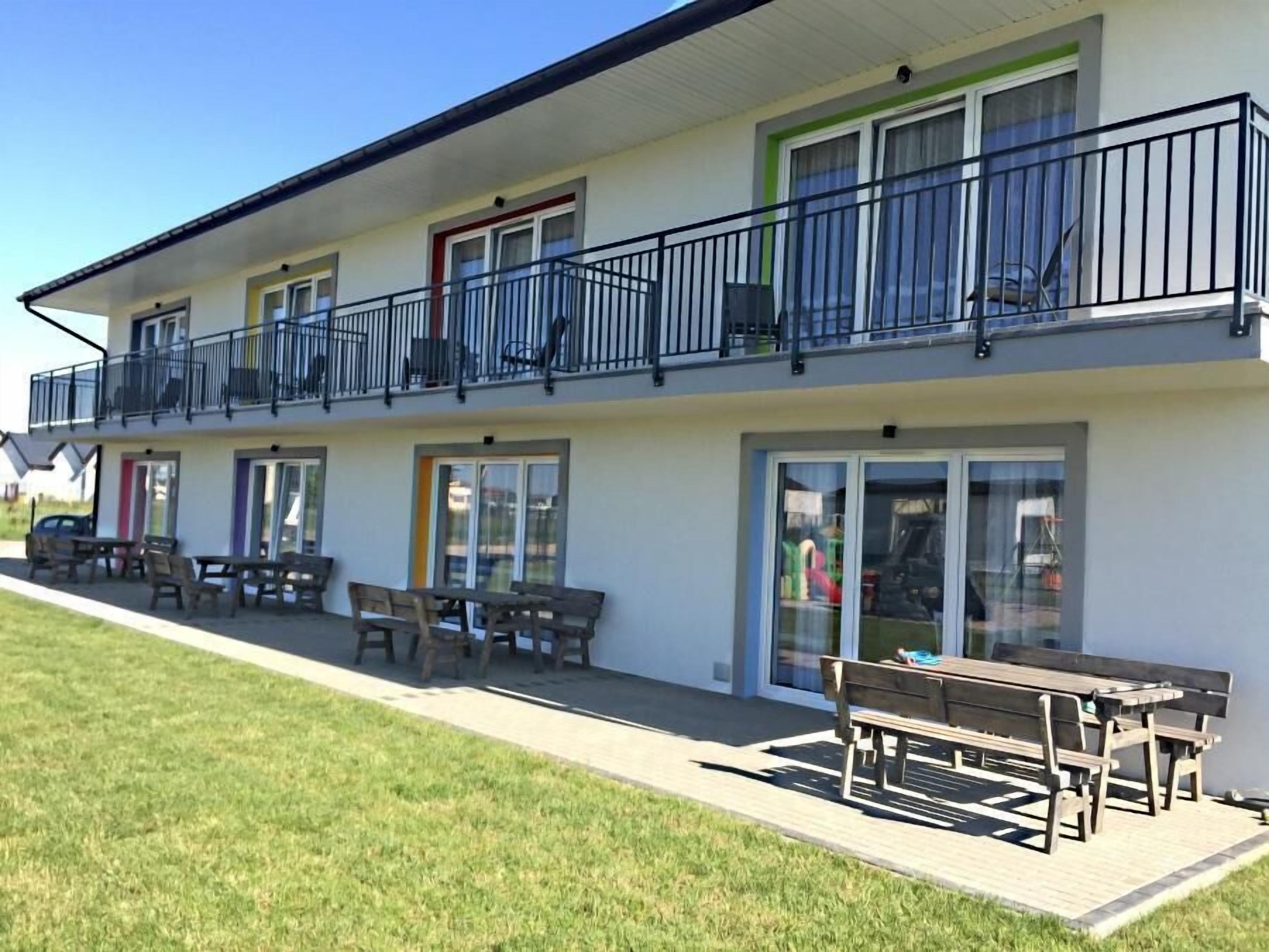 A two-story building with a balcony, outdoor seating area, and a door with a glass panel.