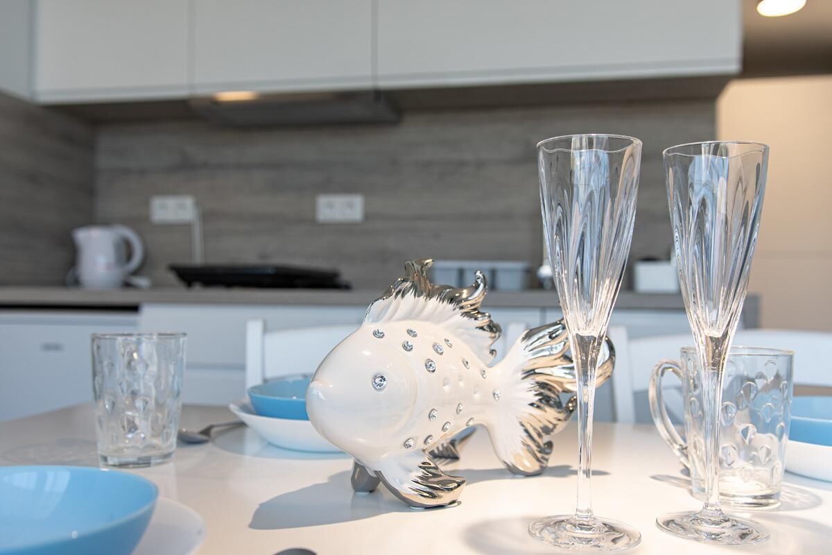 Une cuisine moderne avec un plan de travail blanc, deux grands vases en verre, un ensemble salière et poivrière décoratif en forme de poisson et un bol bleu.