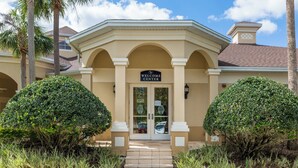 A building with a 'Welcome Center' sign, a covered entrance, and symmetrical landscaping. - Spacious Home W/private Pool/spa & Free Waterpark! (Kissimmee)