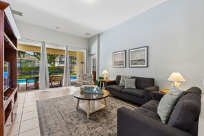 A living room with a sofa, armchair, coffee table, and a view of a pool. - Spacious Home W/private Pool/spa & Free Waterpark! (Kissimmee)