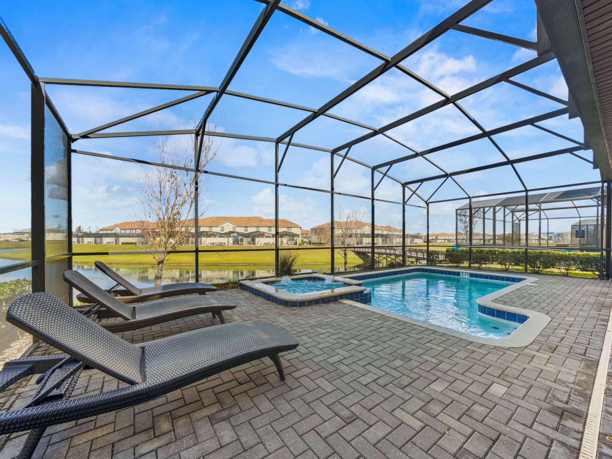 A covered outdoor swimming pool with lounge chairs and a view of a residential area.