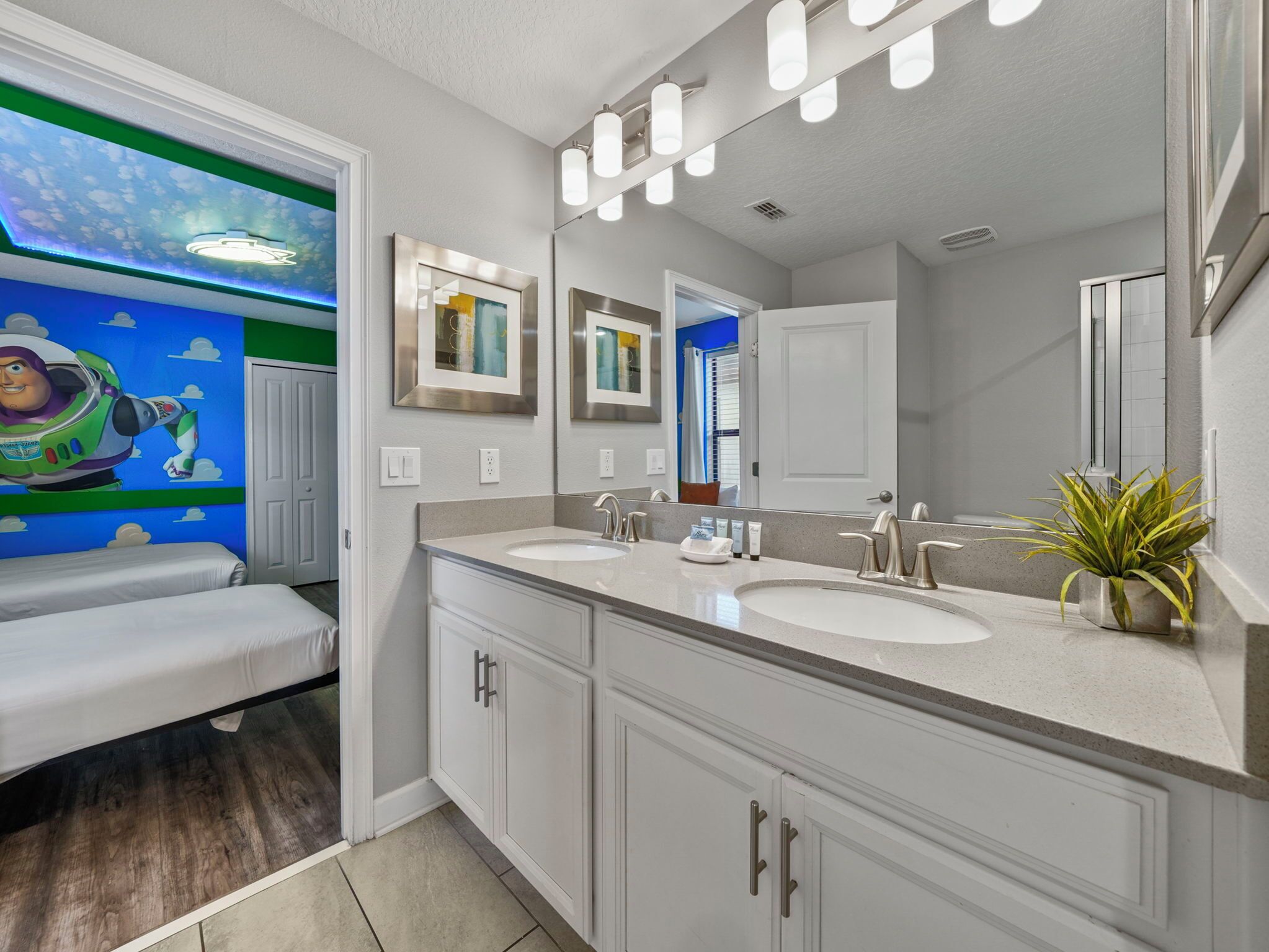 A bathroom with two sinks, a large mirror, and a wall with a space-themed mural.