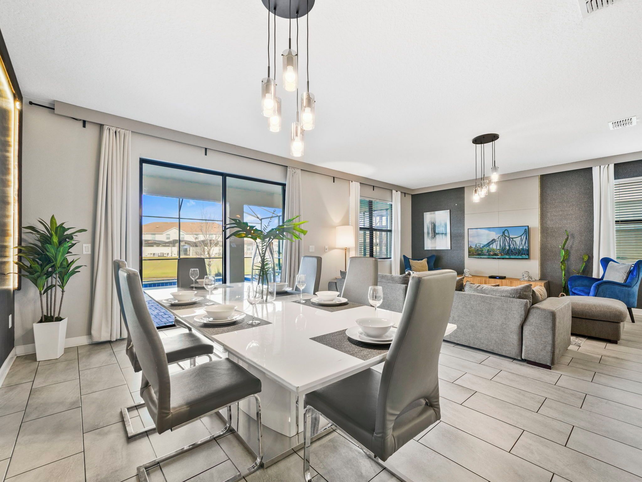 A modern living room with a dining area, large windows, and a view of the outside.