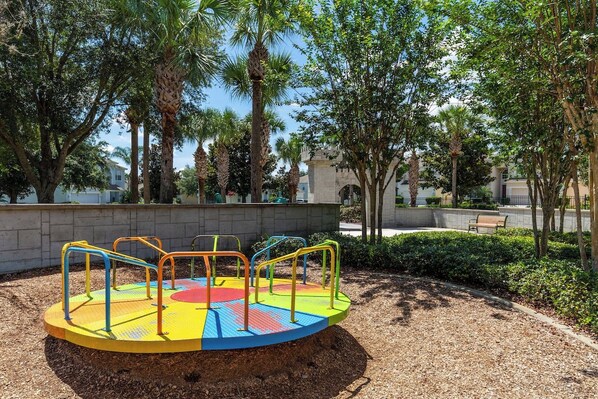A playground with a colorful circular play area and surrounding trees.