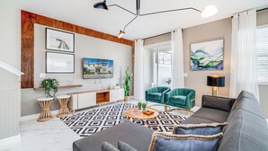 Un salon moderne avec un canapé gris, une table basse, un téléviseur et un fauteuil vert.