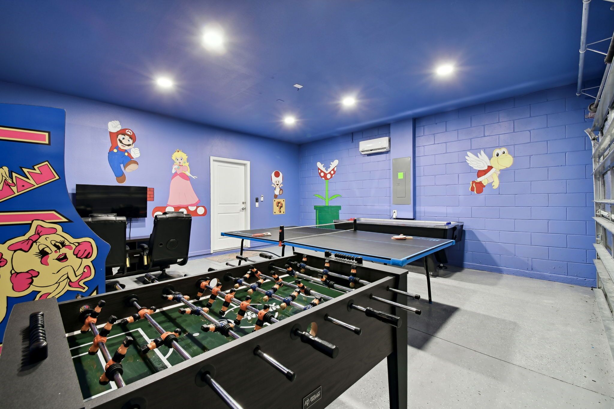 Une pièce avec une table de baby-foot, un téléviseur et une porte.