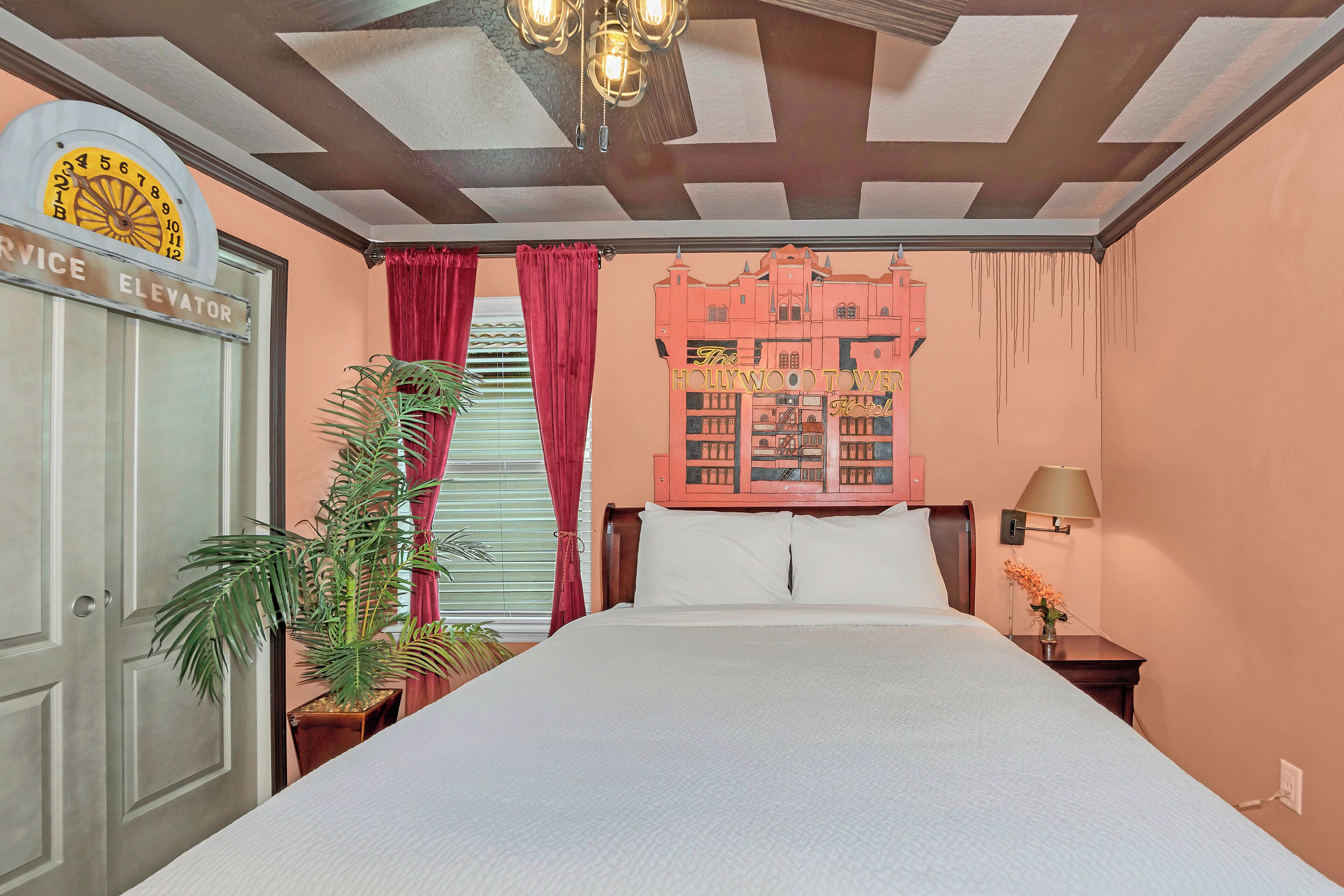 Una habitación de hotel con una cama, un reloj de pared, una planta y un cuadro de un edificio.
