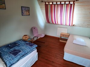 Une chambre avec deux lits, une chaise, un radiateur et une fenêtre avec des rideaux à rayures.