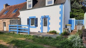 Un bâtiment blanc agrémenté de touches de bleu, un mur en pierre et une clôture bleue.