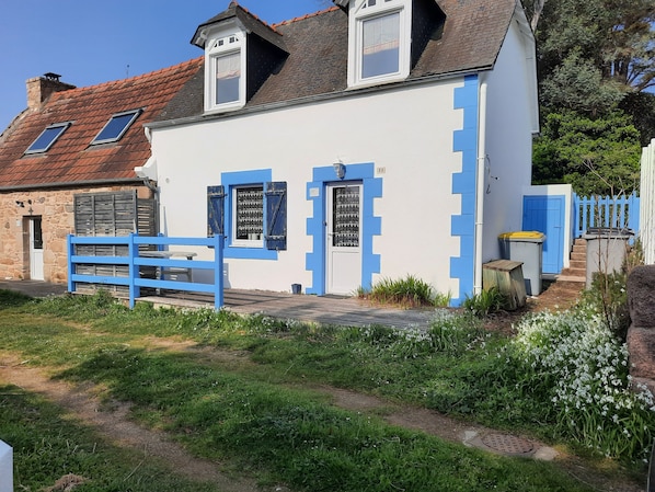 A white building with blue accents, a stone wall, and a blue fence.