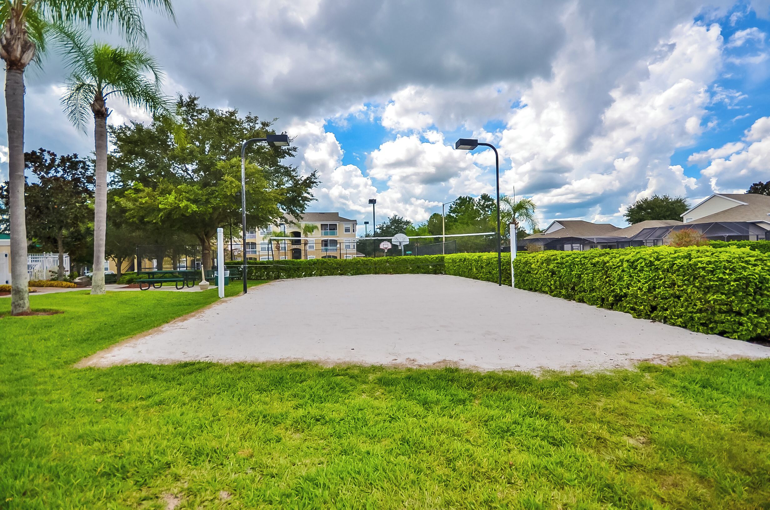 A well-maintained park with a basketball court, surrounded by greenery and residential buildings.