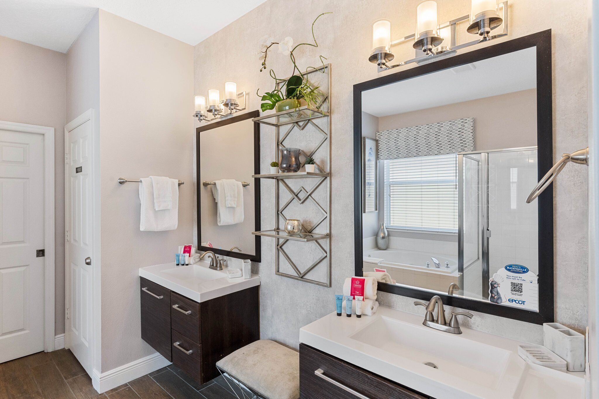 Une salle de bain moderne avec deux lavabos, un grand miroir et une étagère contenant des articles de toilette.