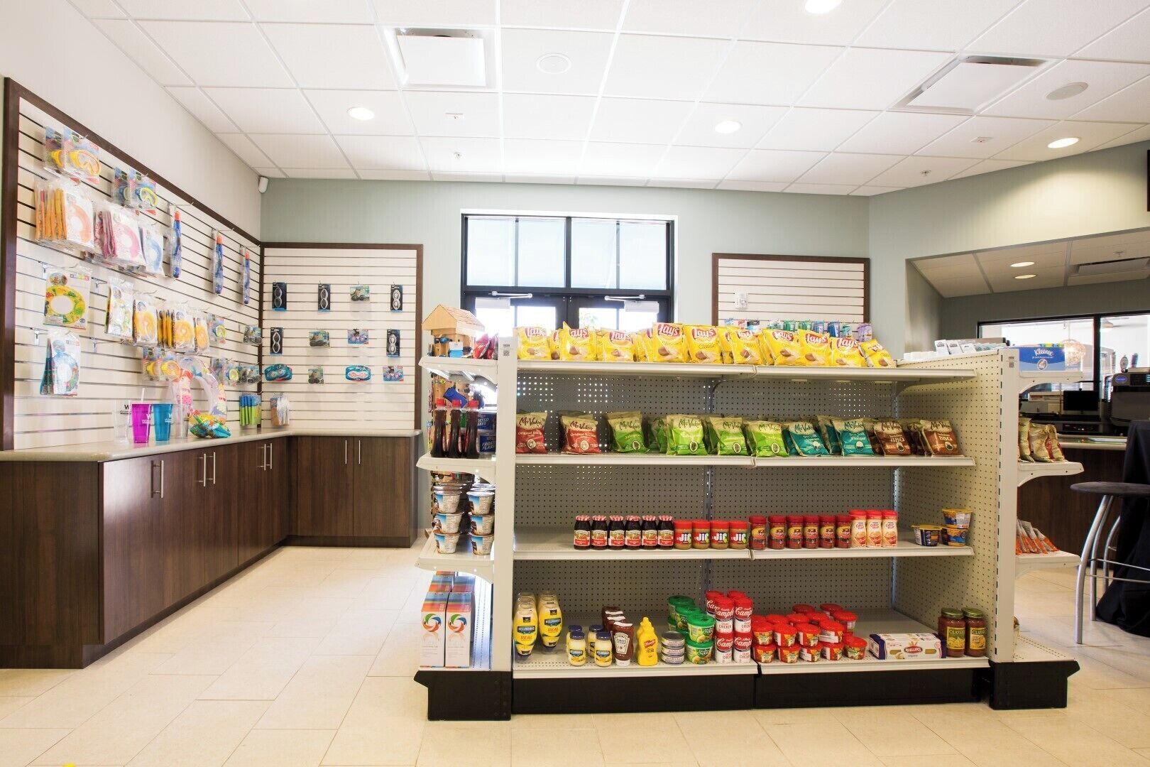 A grocery store interior with shelves stocked with snacks, condiments, and household items.