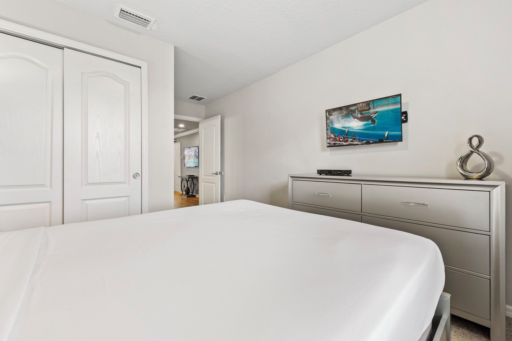 A bedroom with a bed, a dresser, and a painting on the wall.