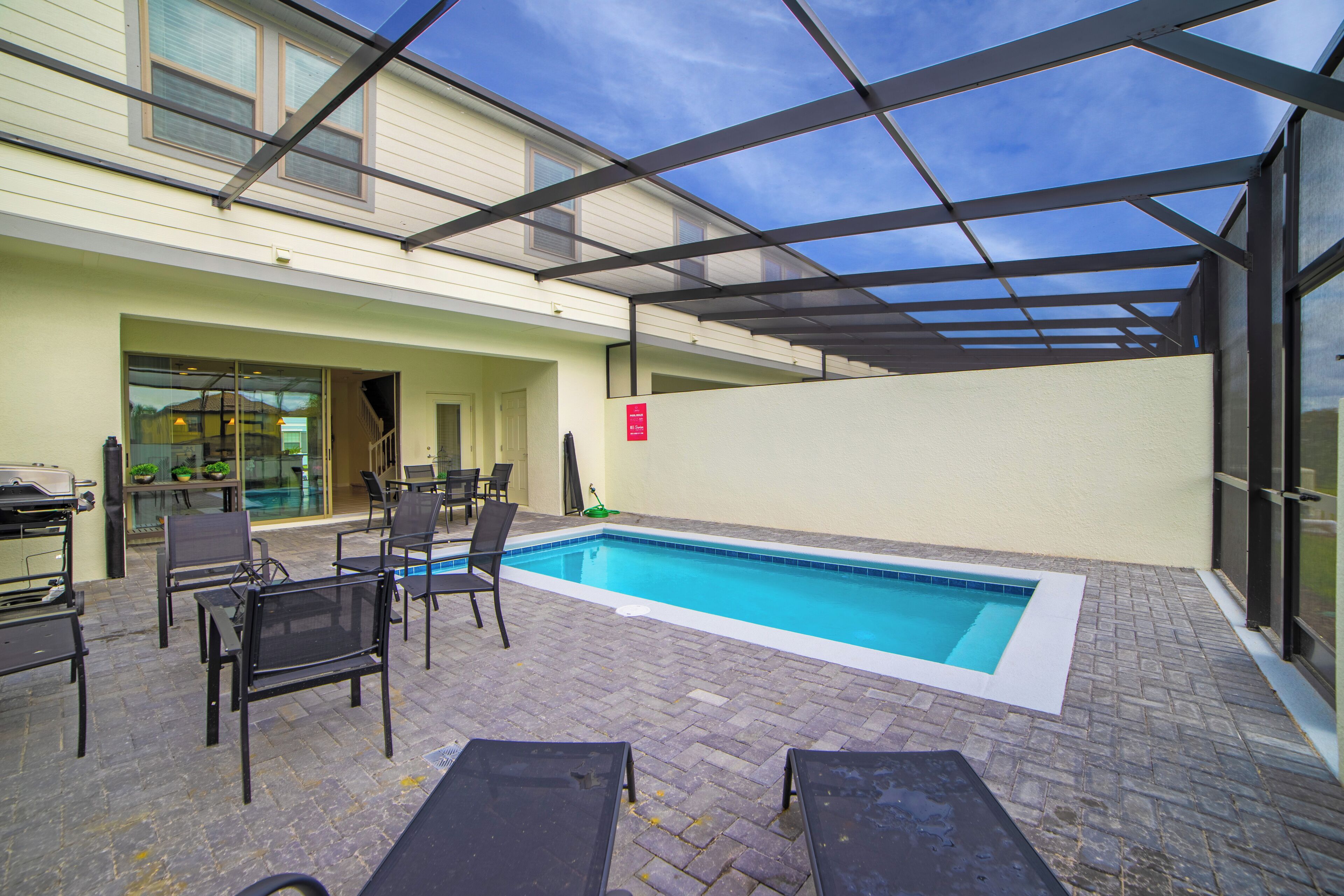An outdoor swimming pool with lounge chairs and a covered patio area.