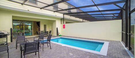 An outdoor swimming pool with lounge chairs and a covered patio area.