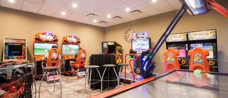 An arcade with racing games, a clock, and stools.