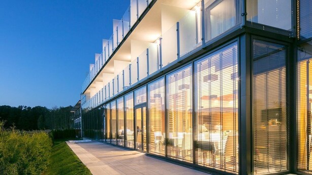 Ein modernes Gebäude mit großen Glasfenstern und einem gepflasterten Weg.
