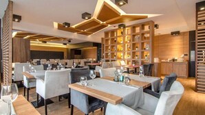 Ein modernes Restaurant mit mehreren Tischen und Stühlen, Holzdetails und einer warmen, einladenden Beleuchtung.