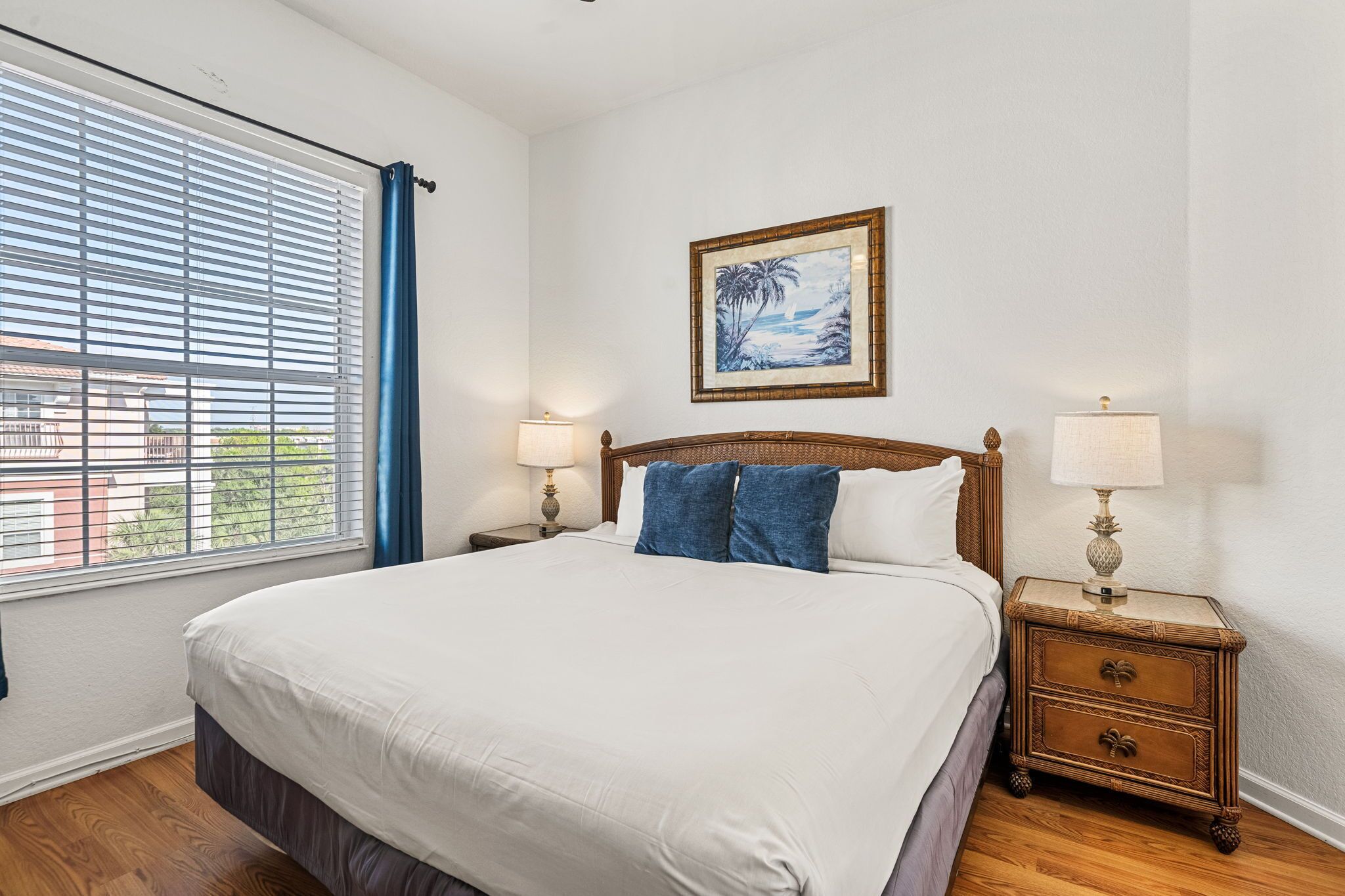 A neatly made bed with white linens, a wooden headboard, and two nightstands with lamps.
