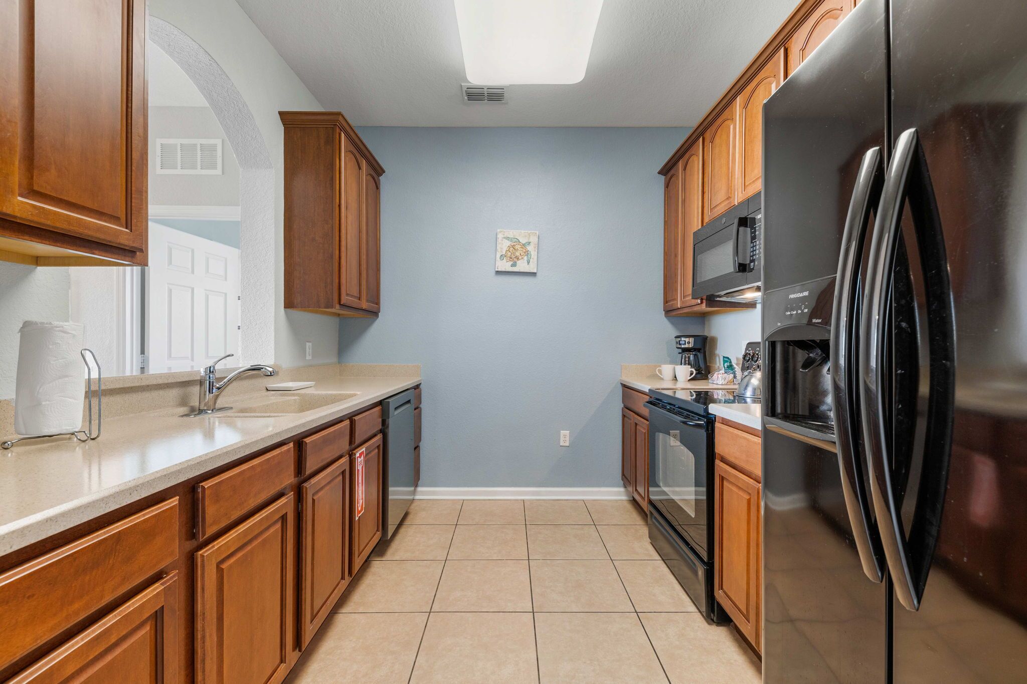 A kitchen with wooden cabinets, a stainless steel refrigerator, a microwave, and a dishwasher.