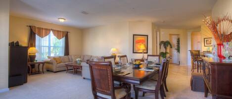 A spacious living room with a dining area, featuring a large wooden table and comfortable seating.