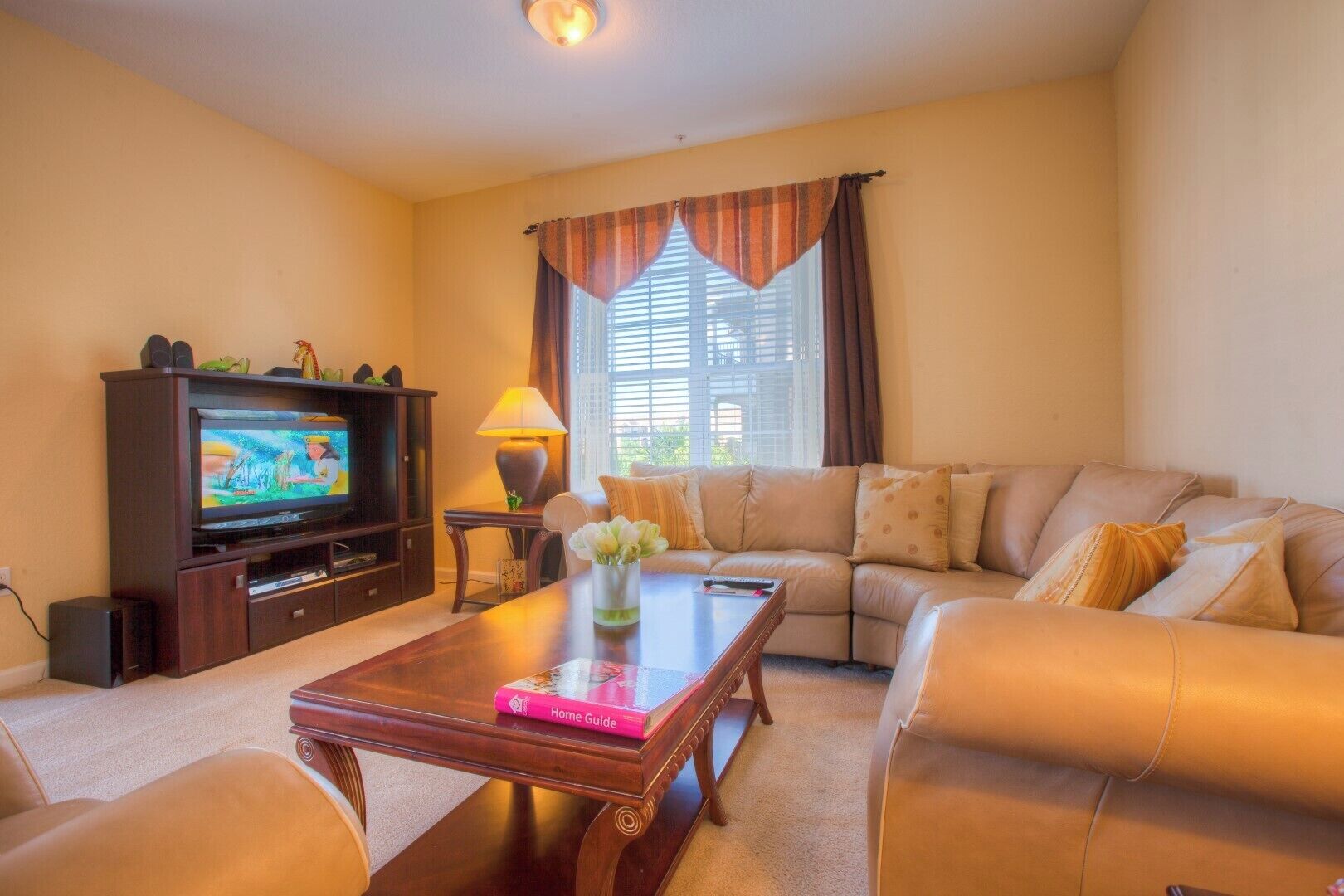 A living room with a television, sofa, coffee table, and a lamp.