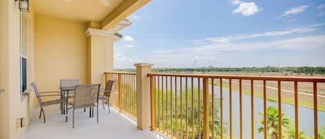 Ein Balkon mit Deckenventilator, Tisch, Stühlen und Blick auf einen Fluss und Grünflächen.