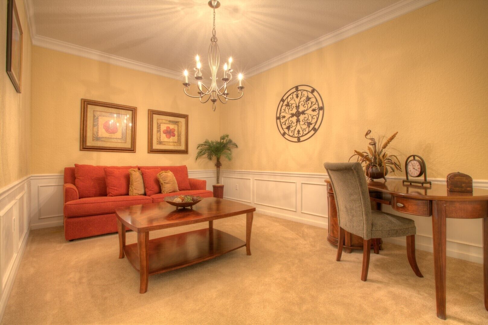 A room with a red sofa, wooden coffee table, and a desk with a chair.