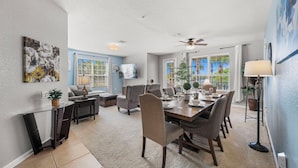 A dining area with a glass table, chairs, and a ceiling fan. - Lakefront Luxury (Orlando)