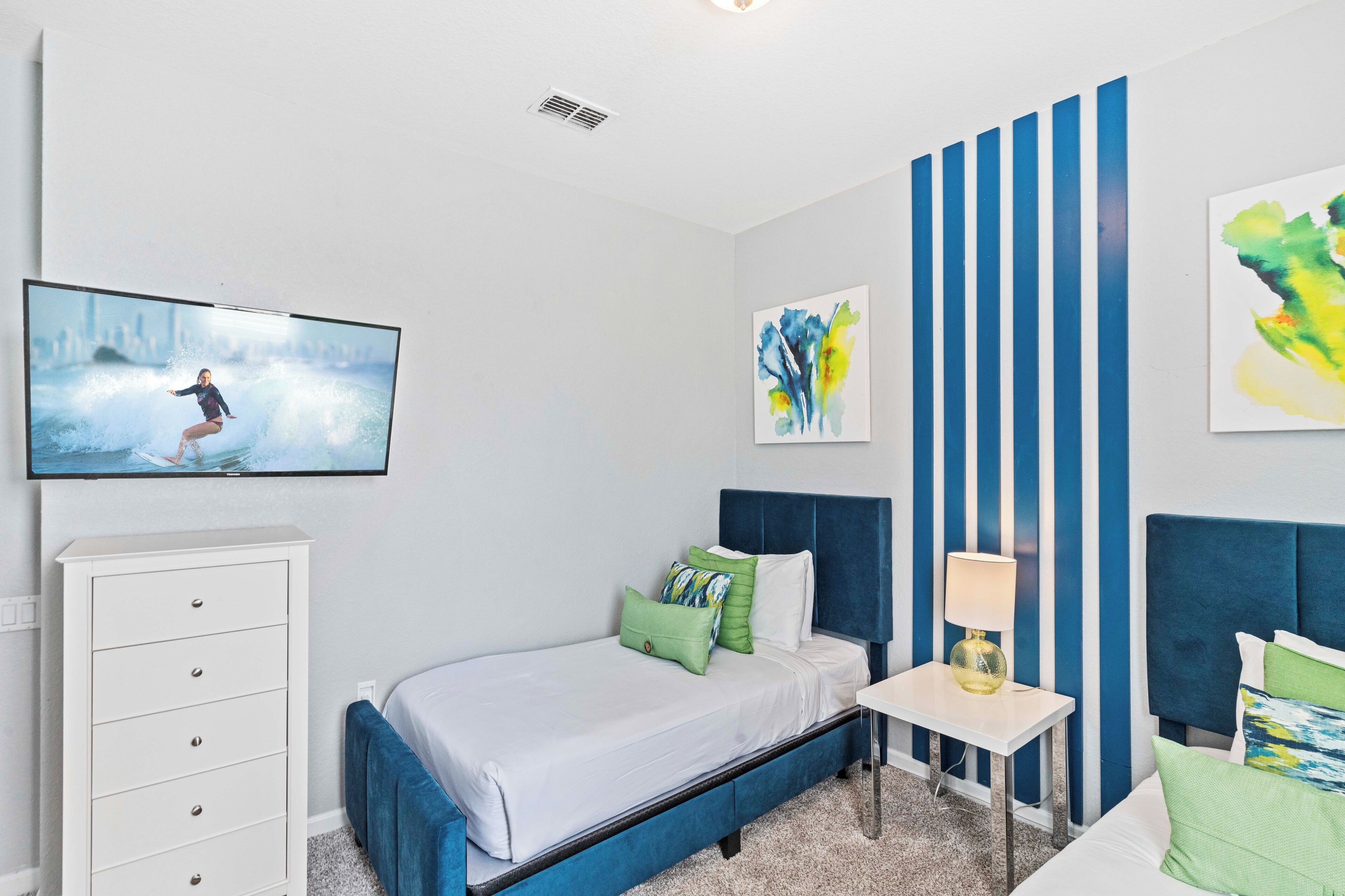 A bedroom with a bed, a dresser, a nightstand, and a TV mounted on the wall.