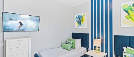 A bedroom with a bed, a dresser, a nightstand, and a TV mounted on the wall.