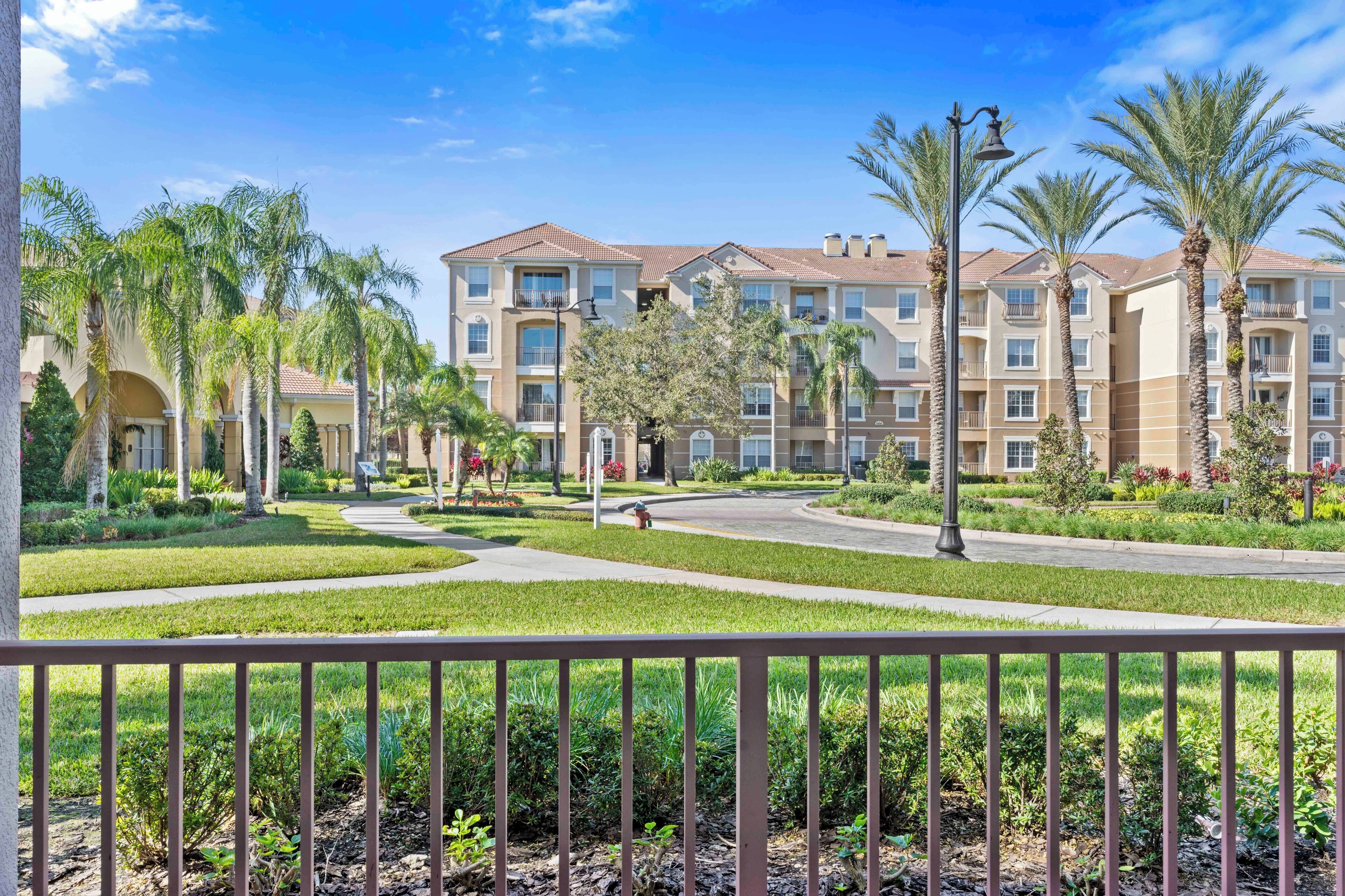 A multi-story residential building with a central courtyard, surrounded by palm trees and well-maintained landscaping.