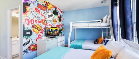Una habitación con literas, un mural de estilo cómic muy colorido, un televisor y una ventana con cortinas.