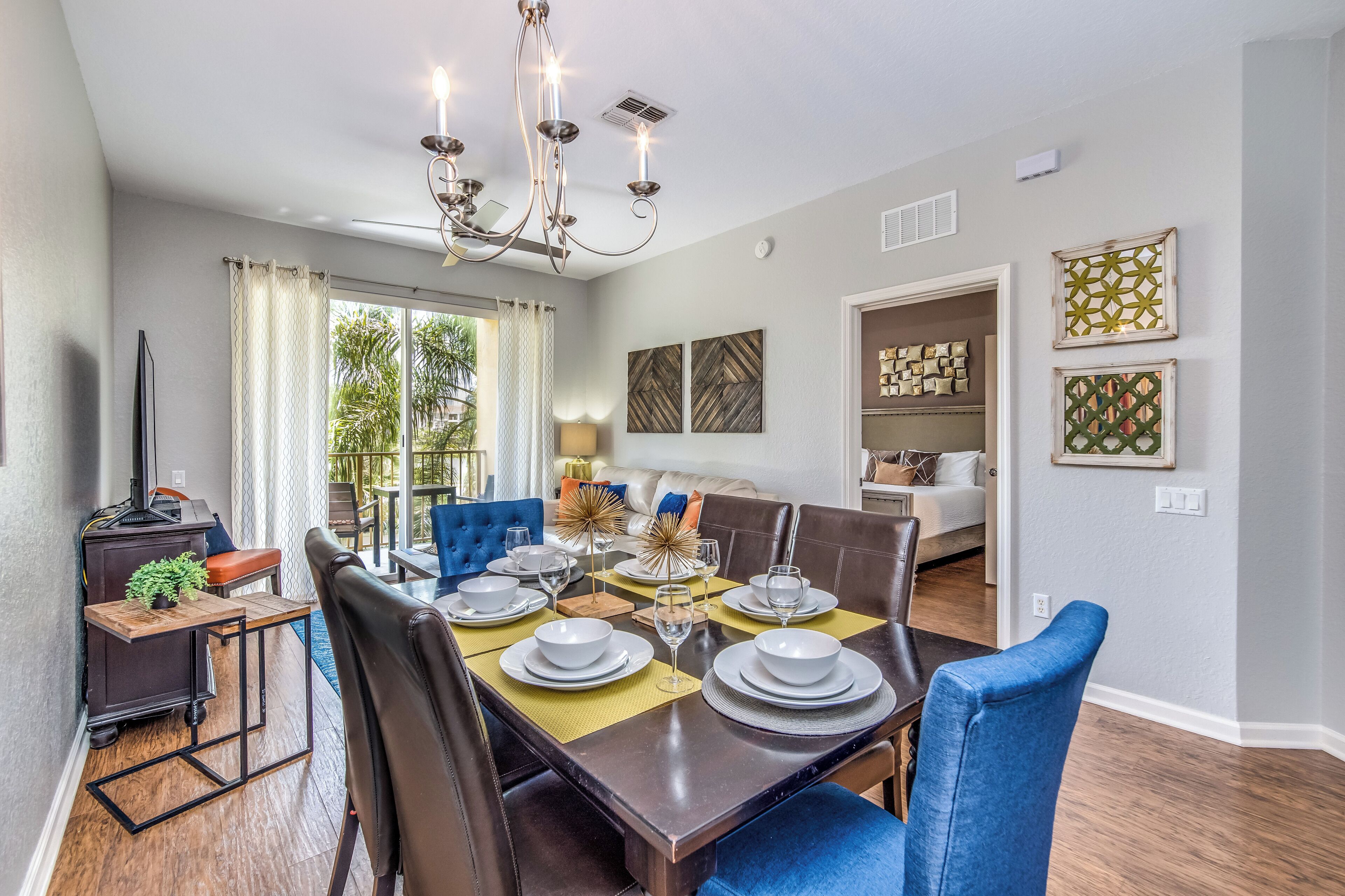 Comedor con una mesa de madera oscura dispuesta para seis personas, rodeada de sillas tapizadas en azul.