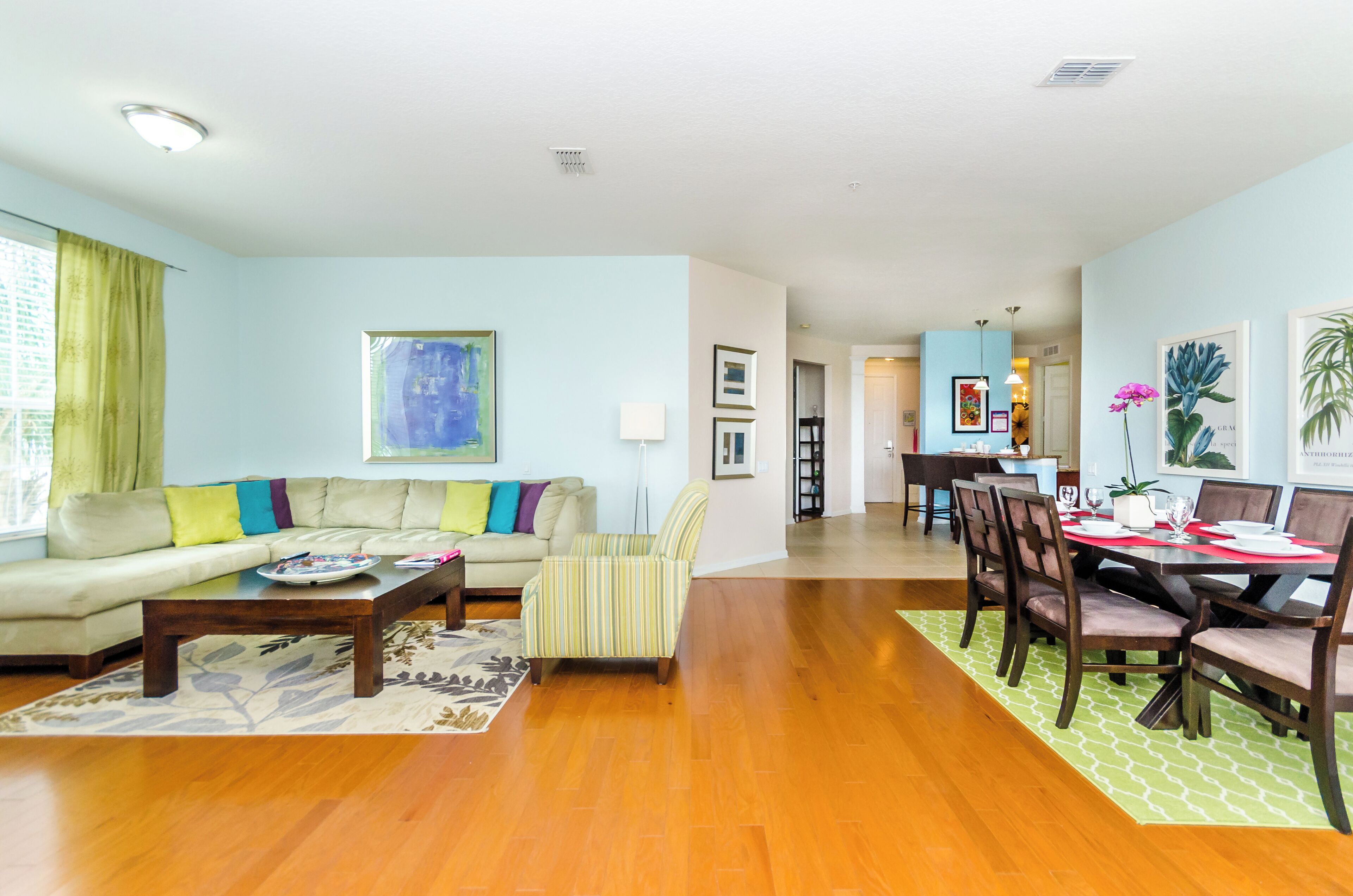 A spacious living room with a sofa, armchair, coffee table, and dining area with chairs and a table.