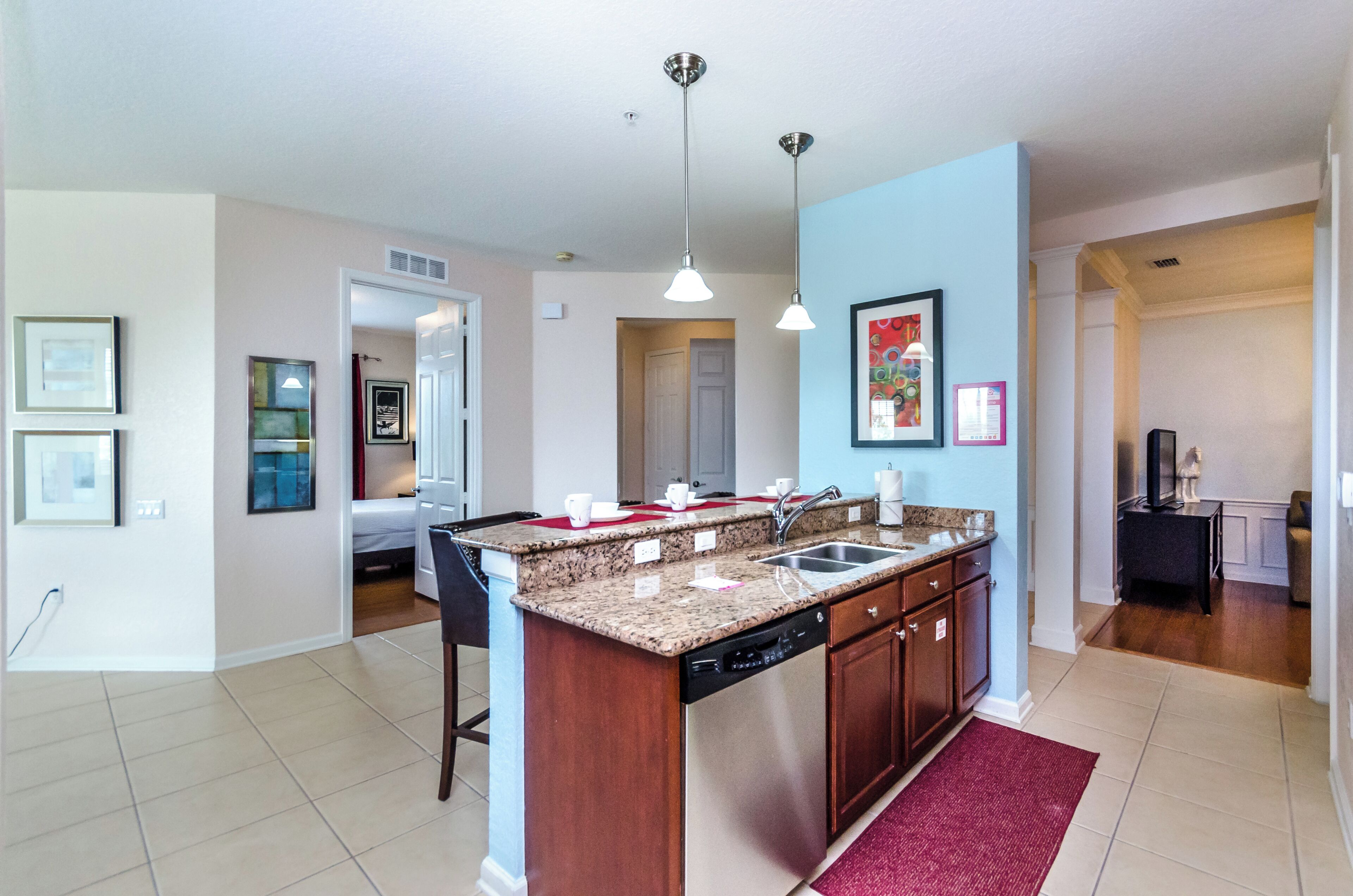 A modern kitchen with granite countertops, stainless steel appliances, and pendant lighting.