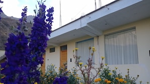 A building with a flat roof, a single entrance door, and a window with a curtain. - El Sol De Oro Hotel (Ollantaytambo)