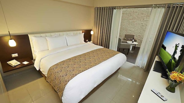 A hotel room with a large bed, a desk with a TV, a chair, and a small table. - El Sol De Oro Hotel (Ollantaytambo)