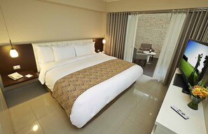 A hotel room with a large bed, a desk with a TV, a chair, and a small table. - El Sol De Oro Hotel (Ollantaytambo)