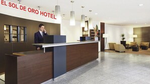 A hotel reception desk with a modern design, a large sign reading "EL SOL DE ORO HOTEL", and a seating area with sofas and a lamp. - El Sol De Oro Hotel (Ollantaytambo)