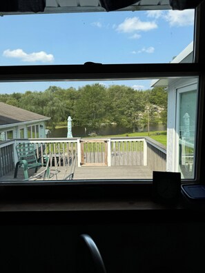 A view from inside a house looking out to a wooden deck with a railing, a green chair, and a small table. - Ski Elk Mountain, hike, walk or bike Rail to Trails, fish, or star gaze. (Union Dale)