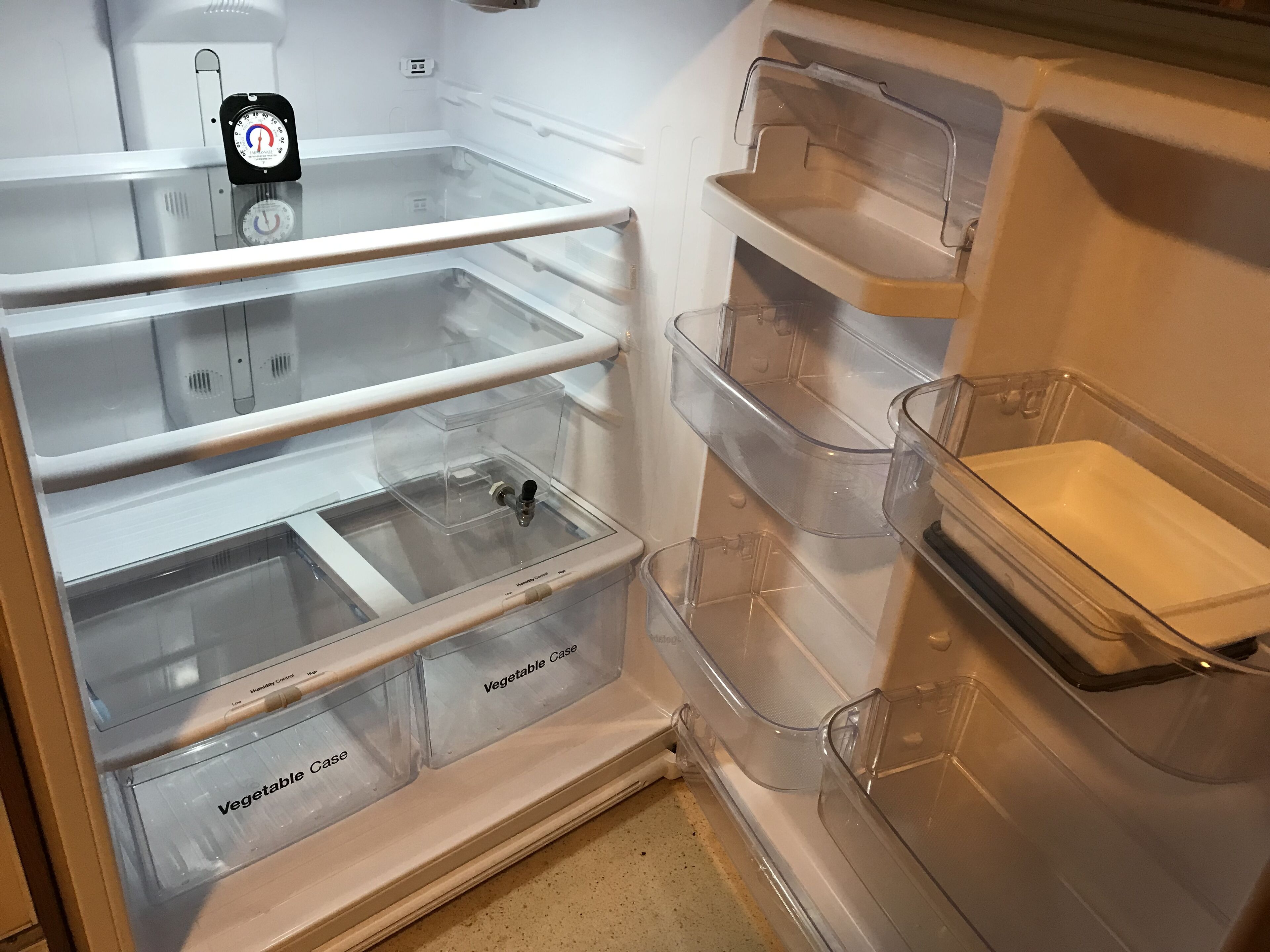 Uma geladeira vazia com várias gavetas transparentes e um dispositivo de controle de umidade na prateleira superior.