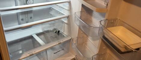 Uma geladeira vazia com várias gavetas transparentes e um dispositivo de controle de umidade na prateleira superior.
