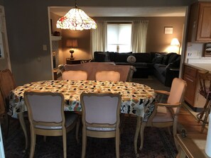 A dining area with a round table covered by a patterned tablecloth, surrounded by four chairs with cushioned seats. A chandelier hangs above the table. - Ski Elk Mountain, hike, walk or bike Rail to Trails, fish, or star gaze. (Union Dale)