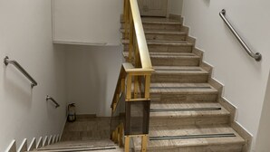 A staircase with wooden handrails, a fire extinguisher, and a door at the top.