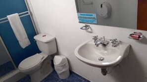 A bathroom with a toilet, sink, and a hand soap dispenser.
