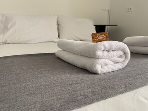 A neatly made bed with a folded white towel and a tag labeled "Suite."
