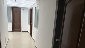 A hallway with a tiled floor, a brown door, and a window with a view of the outside.