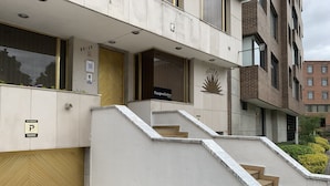 A hotel entrance with a 'No Parking' sign, a staircase leading to the entrance, and a 'Pasajeros' sign indicating guest rooms.
